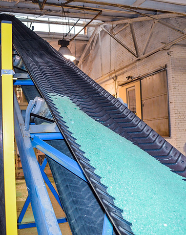Conveyor belt carrying Clearlane Deicer into warehouse from truck outside