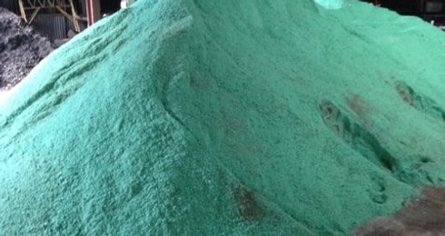 Pile of green Clearlane Enhanced Deicer in warehouse