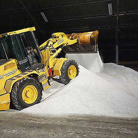 Front loader scopping bulk rock salt from inventory pile