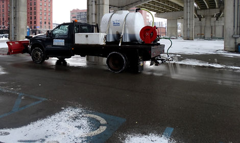 Snow plow truck spraying liquid deicer on roadway